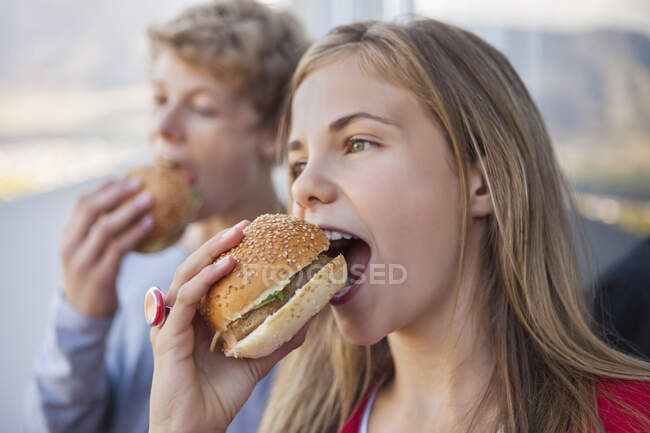Primer plano de dos amigos comiendo hamburguesa - foto de stock