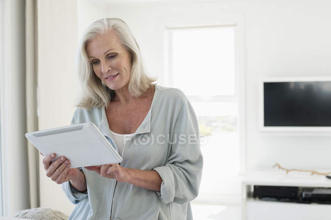 Старша жінка використовує цифровий планшет вдома — стокове фото