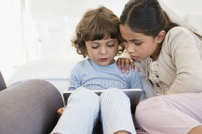 Дівчина дивиться на брата за допомогою цифрового планшета вдома — стокове фото