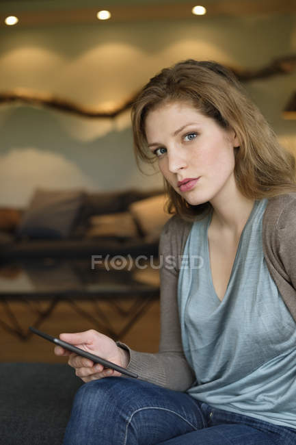 Mulher séria usando tablet digital no sofá no quarto — Fotografia de Stock