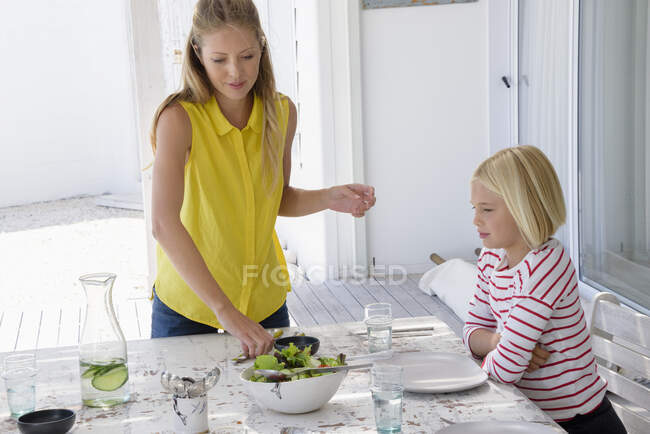 Mère servant de la nourriture à sa fille sur la table — Photo de stock