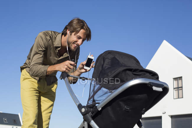 Homme montrant le téléphone portable à bébé dans la poussette — Photo de stock