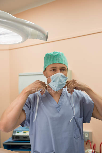 Cirurgião masculino usando máscara cirúrgica na sala de cirurgia — Fotografia de Stock