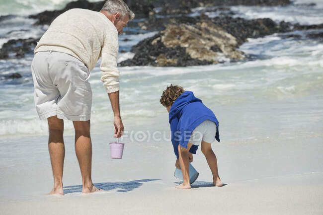 Menino brincando com seu avô na praia — Fotografia de Stock