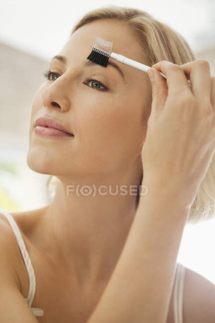 Mujer rubia joven aplicando maquillaje - foto de stock