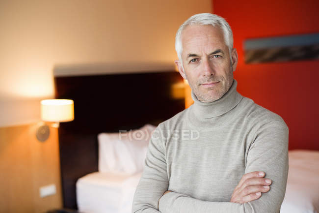 Portrait of mature man with arms crossed in a hotel room — Stock Photo