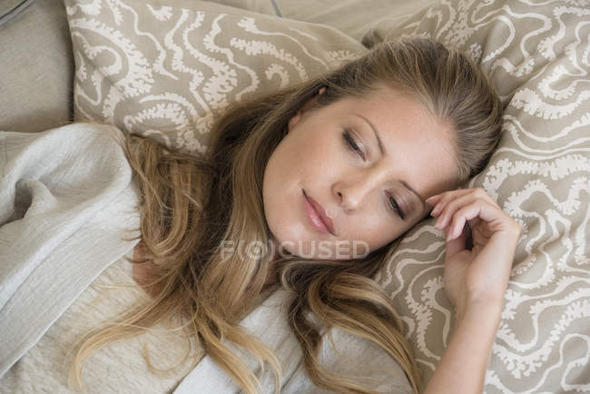 Close-up of thoughtful woman relaxing on couch at home — Stock Photo