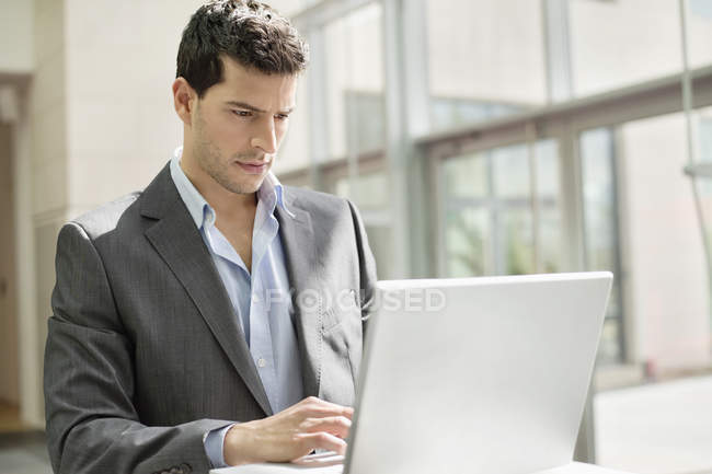Young businessman working on laptop in office — Stock Photo