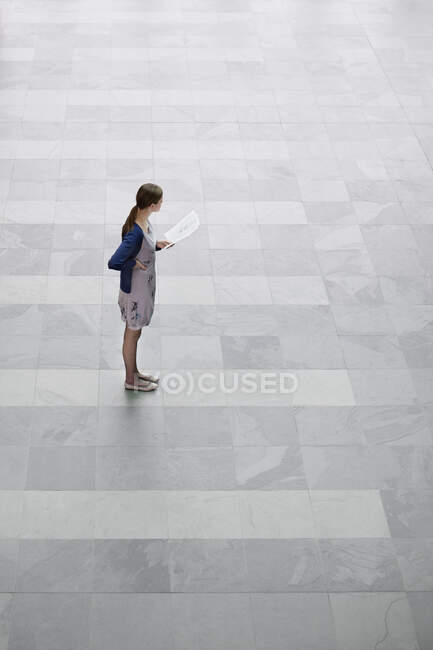 Ділова жінка тримає документи і стоїть в офісному вестибюлі — стокове фото