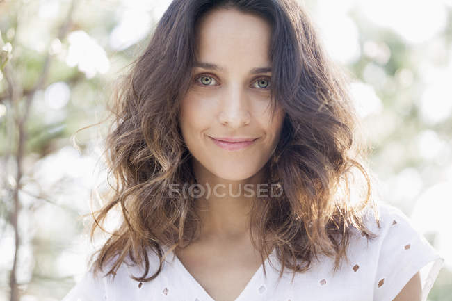 Retrato de mujer sonriendo con el pelo castaño largo al aire libre - foto de stock