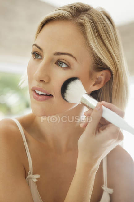Jeune femme blonde appliquant le maquillage — Photo de stock