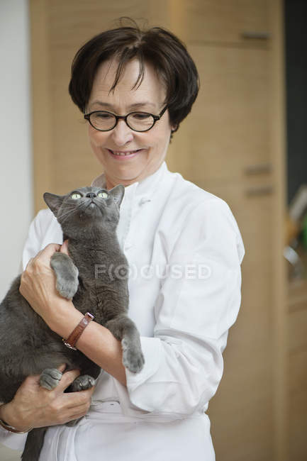 Mature femme tenant chat et souriant — Photo de stock