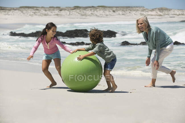 Frau spielt mit ihren Enkeln am Strand — Stockfoto