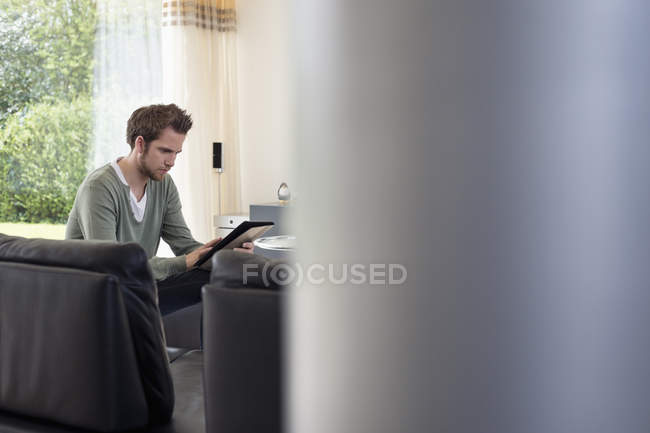 Mann nutzt digitales Tablet zu Hause auf Sofa — Stockfoto