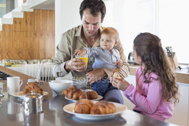 Familia desayunando en un mostrador de cocina - foto de stock