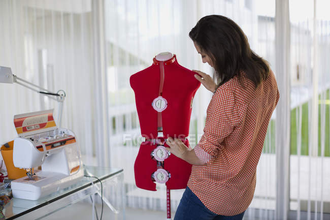 Female fashion designer standing near mannequin — Stock Photo