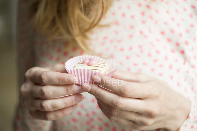 Close-up de mãos femininas segurando cupcake colorido — Fotografia de Stock