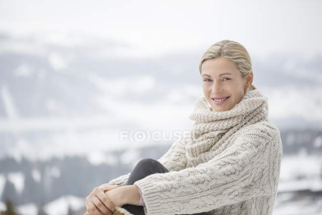 Портрет усміхненої зрілої жінки, яка посміхається в теплому затишному светрі, позує в засніжених горах — стокове фото
