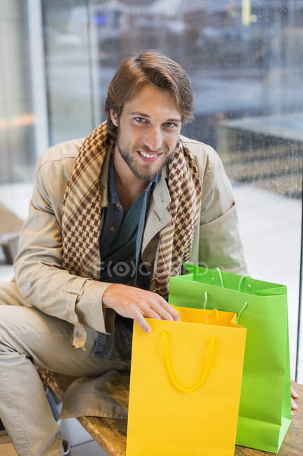 Портрет усміхненого чоловіка, що сидить у вітальні аеропорту з сумками — стокове фото
