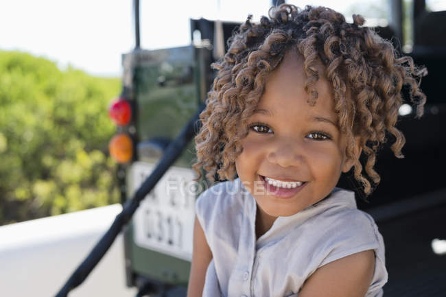 Портрет маленькой девочки, сидящей на улице и улыбающейся — стоковое фото