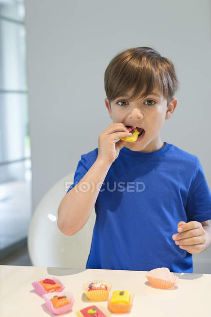 Boy eating sweet cupcake and looking at camera — Stock Photo
