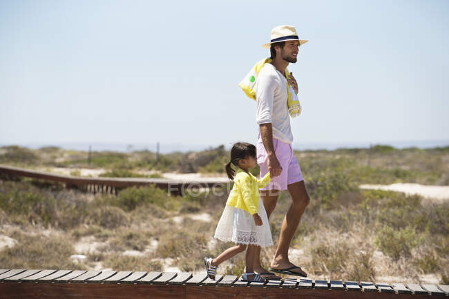 Homem com sua filha andando em um calçadão na praia — Fotografia de Stock