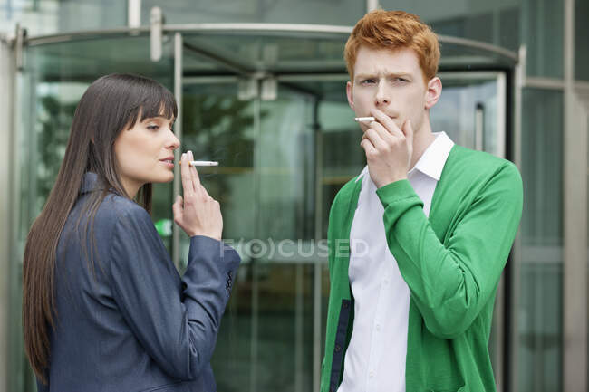 Ejecutivos de negocios fumando frente a un edificio de oficinas - foto de stock