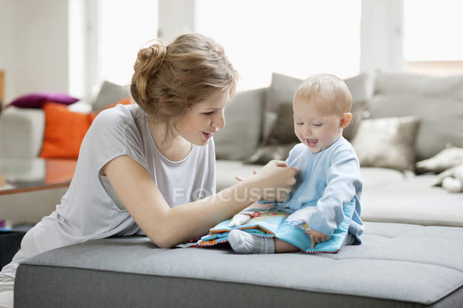 Mujer enseñando a bebé hija con libro de imágenes - foto de stock