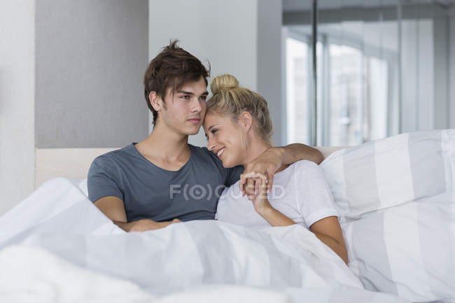 Heureux jeune couple se détendre sur le lit le matin — Photo de stock