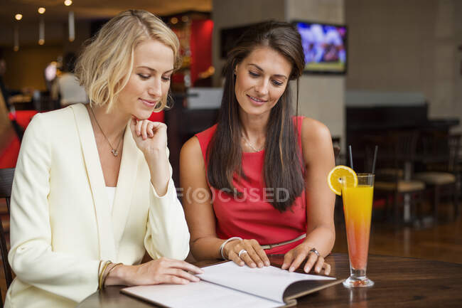 Dos amigas mirando el menú en un restaurante - foto de stock