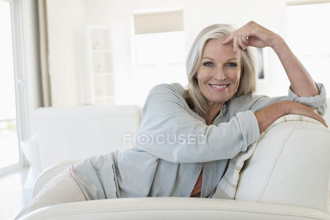 Портрет усміхненої старшої жінки, що сидить на дивані — стокове фото