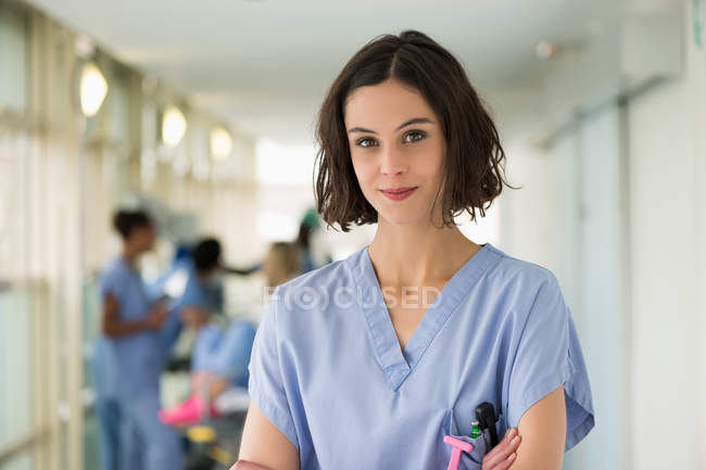 Portrait Of Smiling Female Nurse Standing With Arms Crossed — Expertise Focus On Foreground