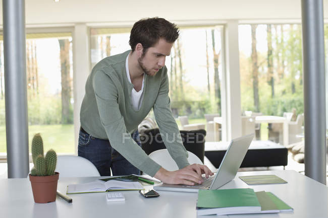 Homme travaillant sur ordinateur portable avec usine de cactus sur la table — Photo de stock