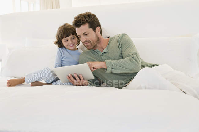 Человек показывает цифровой планшет своему сыну — стоковое фото