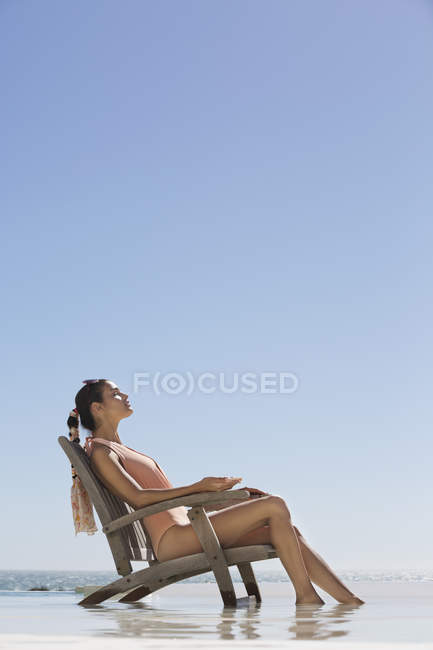 Mulher relaxada elegante sentada na cadeira na praia — Fotografia de Stock