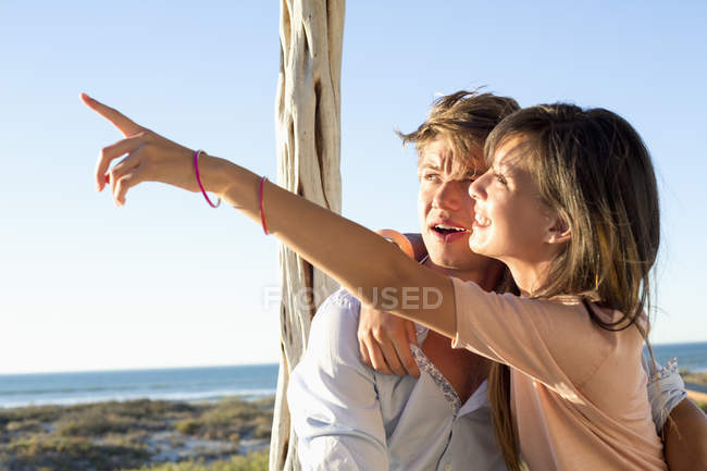 Femme assise avec petit ami sur la côte et pointant du doigt — Photo de stock