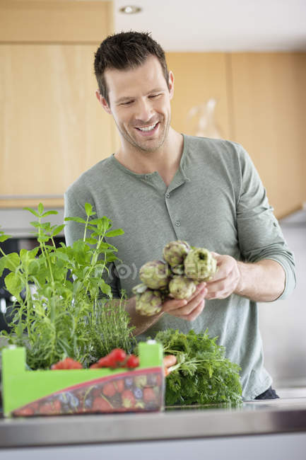 Hombre sonriente guapo preparando comida en la cocina - foto de stock