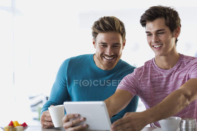 Gros plan de deux jeunes hommes heureux prenant selfie avec une tablette numérique — Photo de stock