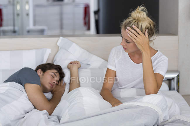 Young woman looking at boyfriend sleeping on bed — Stock Photo