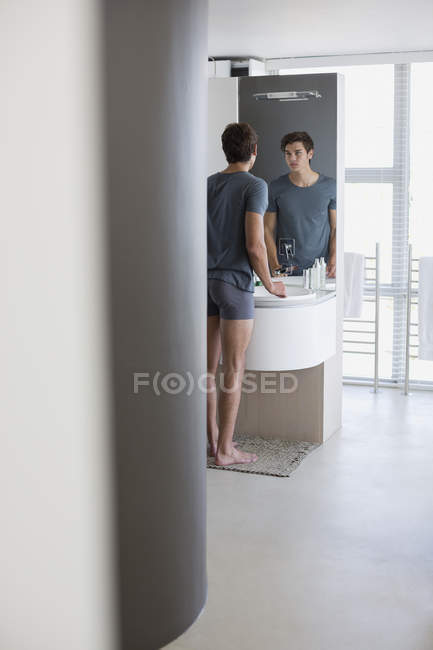 Riflessione dell'uomo guardando specchio del bagno — Foto stock