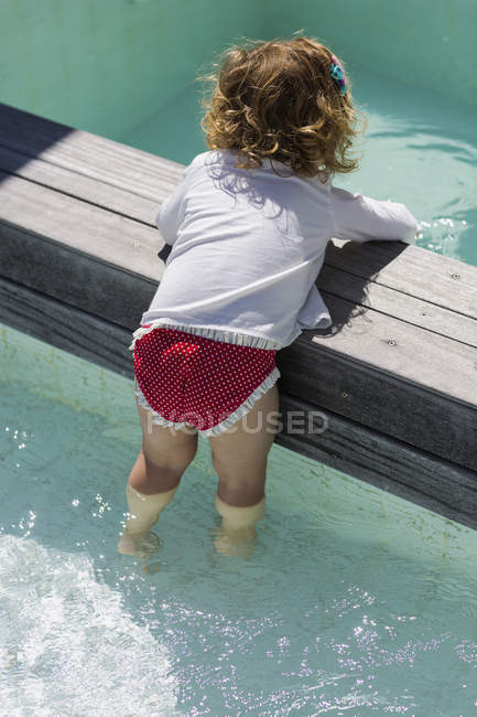 Mignon bébé fille jouer dans infinity pool — Photo de stock