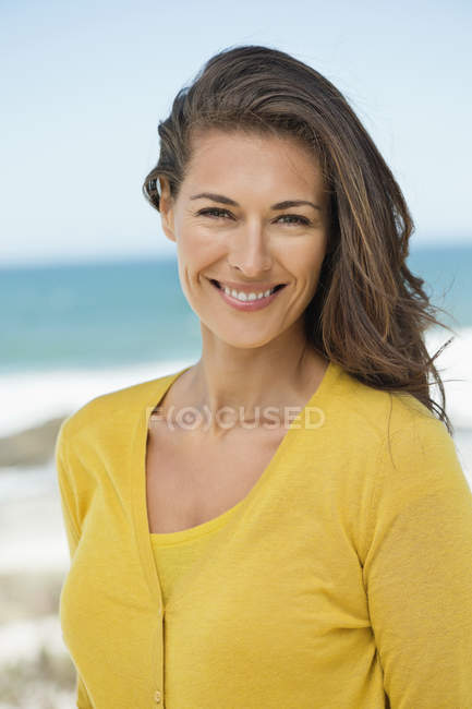 Портрет жінки з коричневим волоссям, посміхаючись на пляжі — стокове фото