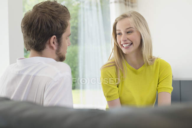 Молодая счастливая пара сидит вместе дома и разговаривает — стоковое фото