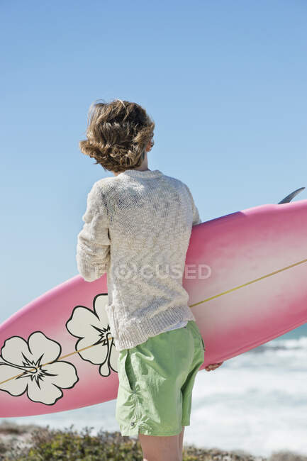 Menino segurando uma prancha na praia — Fotografia de Stock