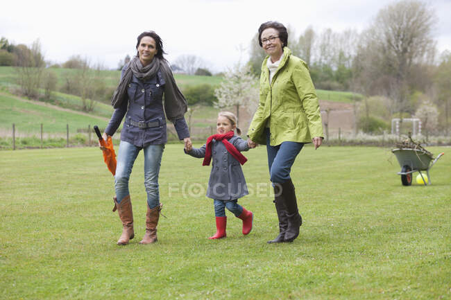 Chica caminando con su madre y su abuela en un césped - foto de stock
