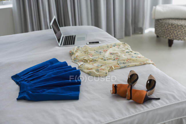 Vestiti e laptop sul letto — Foto stock
