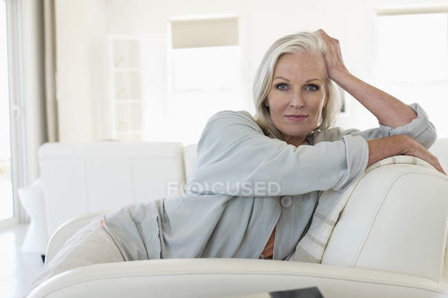 Портрет усміхненої старшої жінки, що сидить на дивані — стокове фото