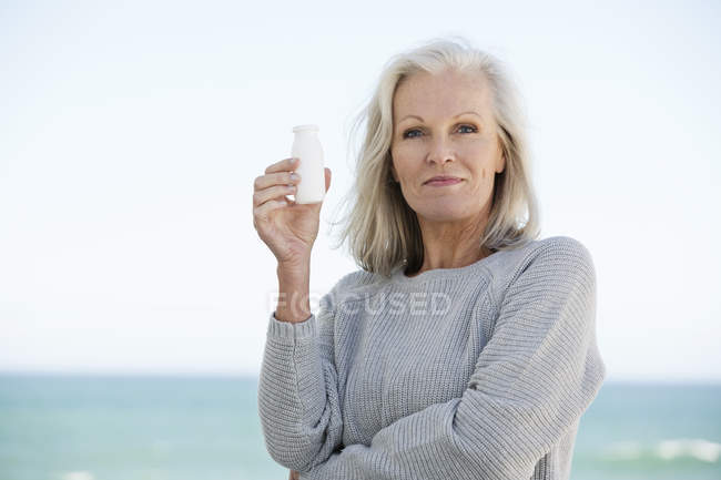 Retrato de mulher segurando garrafa de bebida probiótica na praia — Fotografia de Stock