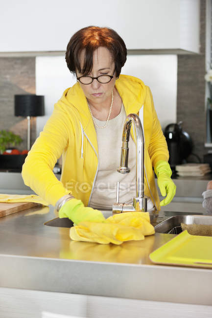 Seniorin putzt Küchenarbeitsplatte — Stockfoto