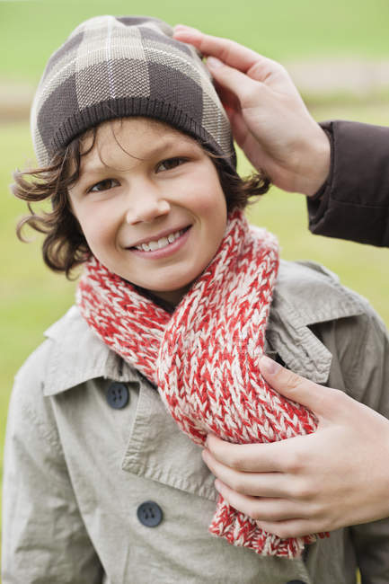 Female hands putting on warm clothing on son outdoors — Stock Photo